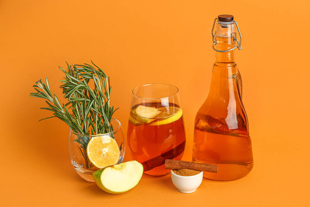 Glass with rosemary, cinnamon powder, bottle and glass of fresh apple juice on color background - Фото, изображение