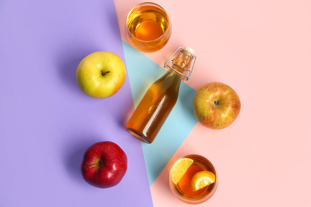 Состав из спелых яблок, бутылок и стаканов свежего сока на цветном фоне - Фото, изображение