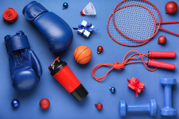 Спортивне обладнання з різдвяними кульками та подарунками на синьому фоні
 - Фото, зображення