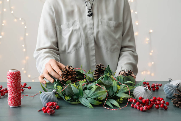 Woman making beautiful Christmas wreath at color wooden table - Valokuva, kuva