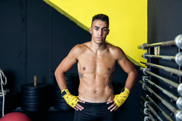 Portrait of a serious young muscular kickboxer looking seriously at the camera. Concept of kickboxing. - 写真・画像
