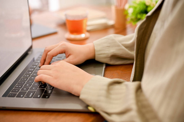close-up εικόνα, Μια γυναίκα εργαζόμενος ή επιχειρηματίας που χρησιμοποιεί φορητό υπολογιστή, πληκτρολογώντας σε πληκτρολόγιο laptop, περιήγηση στο διαδίκτυο. - Φωτογραφία, εικόνα