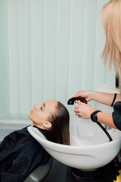 The hairdresser washes the clients hair in the salon. Hair dyeing and cutting. High quality photo - Фото, зображення