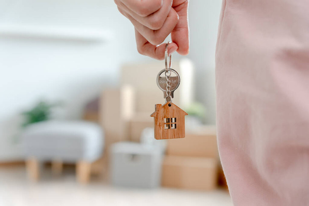 Переезд, переезд. Женщина держит брелок для ключей в новой квартире. переехать в новый дом. Купить или арендовать недвижимость. аренда квартир, аренда недвижимости, новый арендодатель, жилье, кредит, ипотека - Фото, изображение