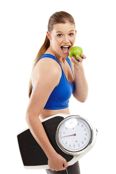 Apples - her new favorite snack. A pretty teenager holding an apple in her hand while carrying a scale - Photo, Image