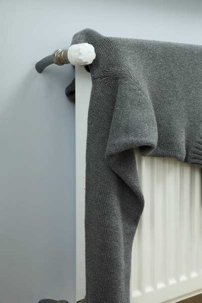 Secado de suéter gris en un radiador interior - Foto, imagen
