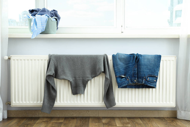 Pull gris et jeans séchant sur un radiateur intérieur - Photo, image