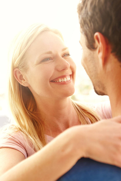 Compartiendo un momento. Una feliz pareja bajo el sol abrazándose y sonriendo - Foto, imagen