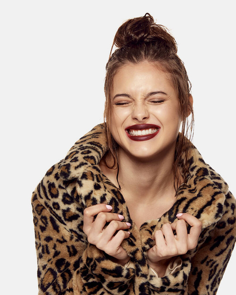 Portrait of young beautiful girl posing in stylish animal print coat and emotionally smiling isolated over white background. Concept of beauty, skin care, cosmetology, plastic surgery, makeup - Fotografie, Obrázek