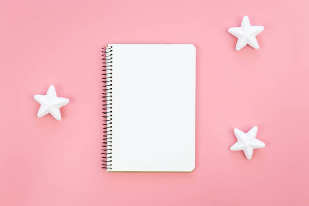 Blank notepad on pink background and decorative stars, flat lay, place for a wish list, gifts or goals for the year. - Foto, Bild