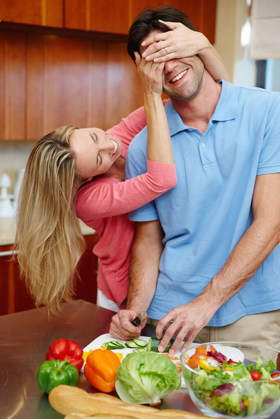 Διασκέδαση στην κουζίνα. ένα ερωτευμένο παντρεμένο ζευγάρι να είναι παιχνιδιάρικο ενώ ετοιμάζει φαγητό στην κουζίνα - Φωτογραφία, εικόνα