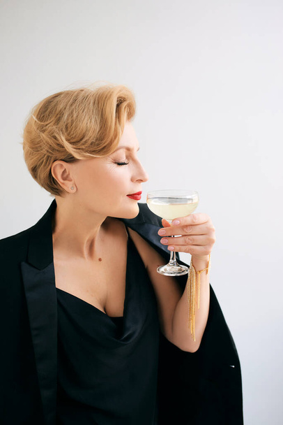 mature stylish elegant woman in tuxedo with glass of sparkling wine. Party, celebration, anti age concept  - Фото, изображение