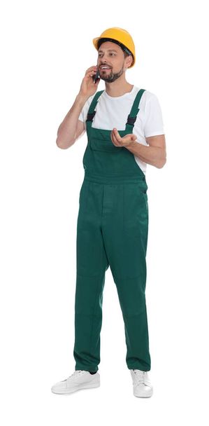 Professional repairman in uniform talking on phone against white background - Photo, image