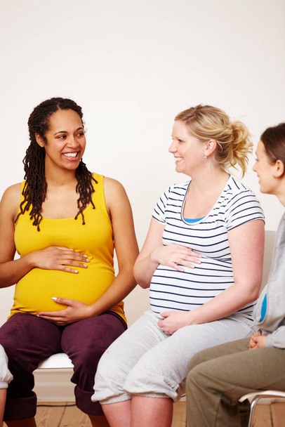 Ти маєш нашу підтримку. Багатоетнічна група вагітних жінок, які посміхаються один одному, сидячи і торкаючись їх черева
 - Фото, зображення