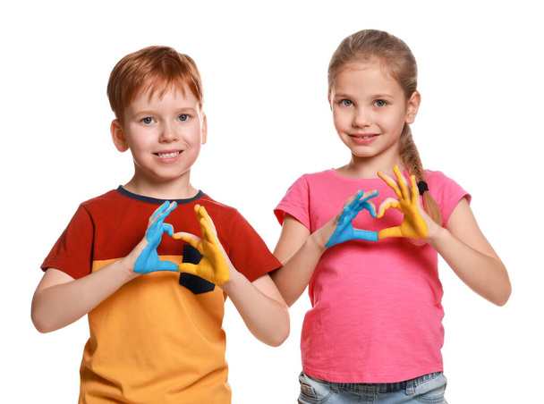 Little girl and boy making heart with their hands painted in Ukrainian flag colors on white background. Love Ukraine concept - Фото, изображение