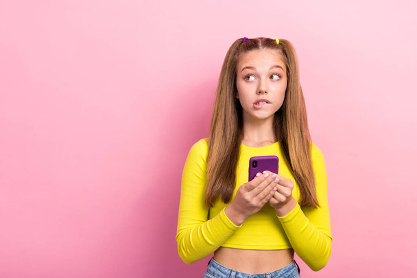 Photo of worried nervous lady wear stylish clothes look empty space bite lips failure spoiled new gadget isolated on pink color background. - Foto, Bild