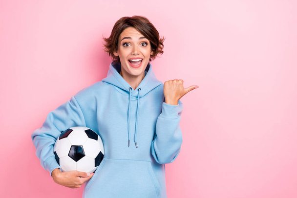 Photo of young pretty attractive cute nice woman wear sport costume hoodie football ball excited positive finger directing empty space isolated on pink color background. - Φωτογραφία, εικόνα
