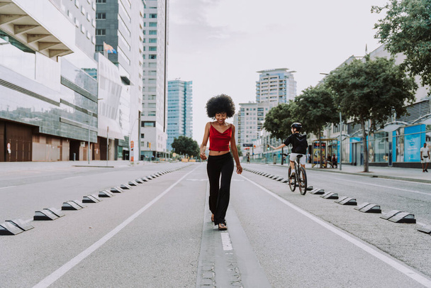 Beautiful young happy african woman with afro curly hairstyle strolling in the city - Cheerful black student walking on the streets - Photo, image