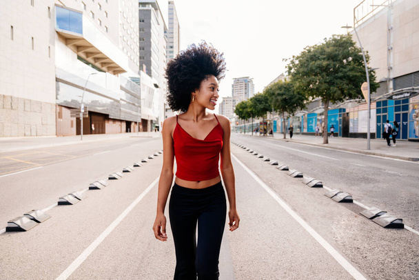 Beautiful young happy african woman with afro curly hairstyle strolling in the city - Cheerful black student walking on the streets - Foto, afbeelding