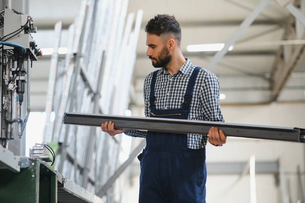 Worker at a window production factory selecting a specific PVC profile panel. - Foto, Imagem