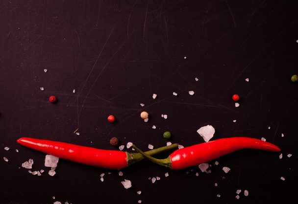 Red hot chilli pepper with sea salt and colored pepper on black  - Photo, Image