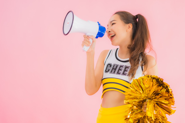 Portrait beautiful young asian woman cheerleader with megaphone on pink isolated background - Photo, Image