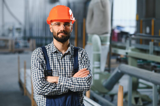 Happy Professional Heavy Industry Engineer Worker Wearing Uniform, and Hard Hat in a Steel Factory. Smiling Industrial Specialist Standing in a Metal Construction Manufacture. - Фото, изображение