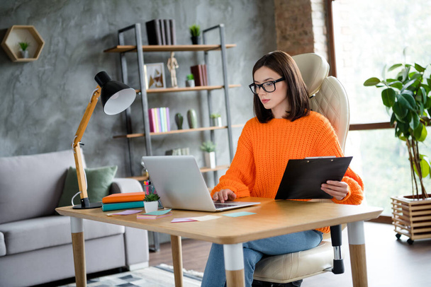 Photo of serious busy lady dressed orange pullover checking working list modern gadget indoors workshop workplace workstation. - Foto, Imagen