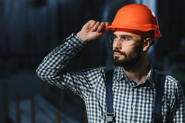 Happy Professional Heavy Industry Engineer Worker Wearing Uniform, and Hard Hat in a Steel Factory. Smiling Industrial Specialist Standing in a Metal Construction Manufacture. - Foto, afbeelding