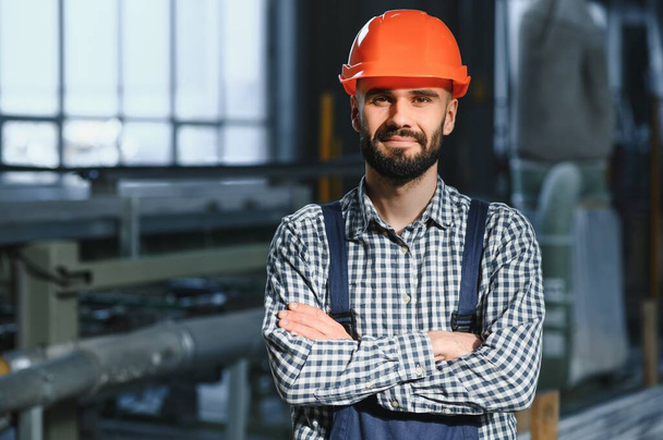 Happy Professional Heavy Industry Engineer Worker Wearing Uniform, and Hard Hat in a Steel Factory. Smiling Industrial Specialist Standing in a Metal Construction Manufacture. - Fotografie, Obrázek