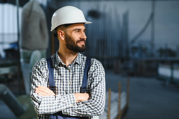 Portrait of industrial engineer. Factory worker with hard hat standing in factory - Фото, изображение