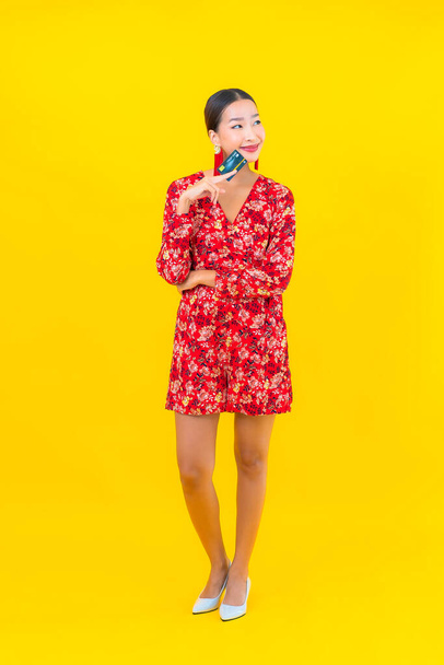 Portrait beautiful young asian woman credit card for shopping on yellow isolated background - Foto, immagini