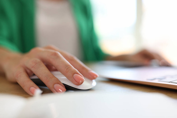Zbliżenie kobiety za pomocą myszki komputerowej pracującej na nowoczesnym laptopie w biurze. Biznesmenka w miejscu pracy. Koncepcja dnia pracy - Zdjęcie, obraz