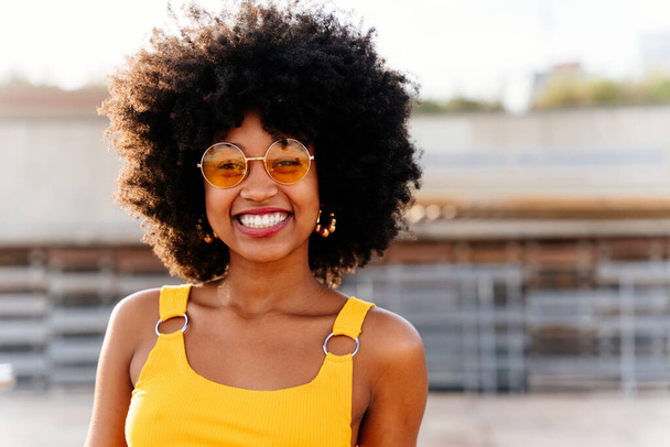 Güzel, genç, mutlu, afro kıvırcık saçlı Afrikalı bir kadın şehirde geziyor. - Fotoğraf, Görsel