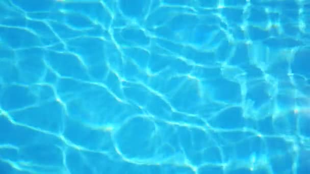Acqua cristallina con luce solare increspata in piscina. I raggi di sole lucenti che riflettono e scintillano su superficie d'acqua. Bello sfondo. Rallentatore Primo piano Vista dall'alto. - Filmati, video