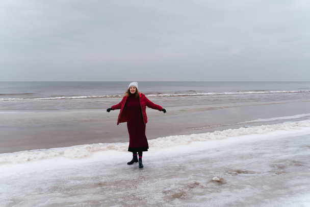 Radostná žena v červeném saku a šaty u moře v zimě. - Fotografie, Obrázek