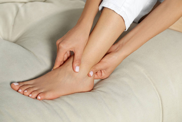 Woman rubbing sore foot on sofa, closeup - Foto, Imagen