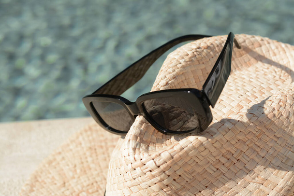 Stylish hat and sunglasses on blurred background, closeup - Zdjęcie, obraz