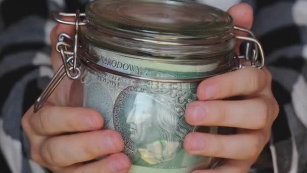 Polish zloty banknote saving money in glass jar. Unrecognizable woman moderate consumption and economy Collecting money. Tips. Business, finance, saving, banking and people concept. Extra money - Filmagem, Vídeo