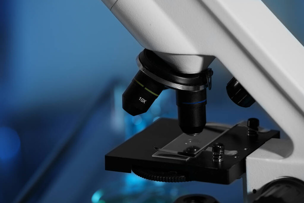 Nahaufnahme des modernen Mikroskops mit Glasschieber auf unscharfem Hintergrund, in blau getönt. Raum für Text - Foto, Bild