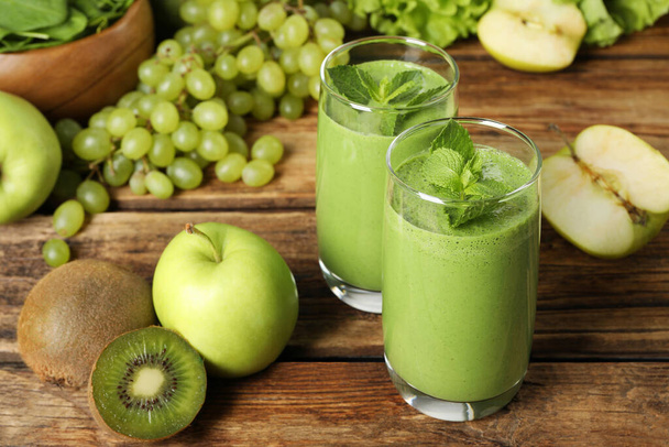 Green smoothie in glasses and fresh ingredients on wooden table - Φωτογραφία, εικόνα