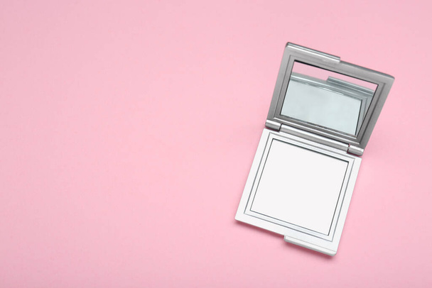 Stylish cosmetic pocket mirror on pink background, top view. Space for text - Foto, Imagem
