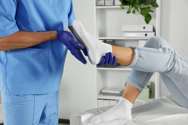 Male orthopedist fitting insole to patient's foot in hospital, closeup - Φωτογραφία, εικόνα