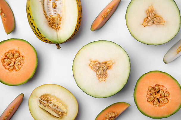Cut different types of melons on white background, flat lay - Фото, изображение