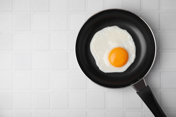 Tasty fried egg in pan on white table, top view. Space for text - Фото, изображение