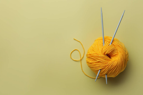 Soft woolen yarn and knitting needles on yellow background, top view. Space for text - Foto, Imagem