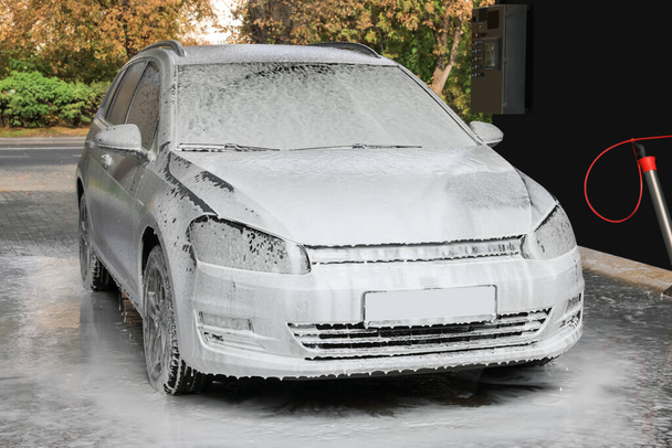 Auto with cleaning foam at outdoor car wash - Foto, Imagen