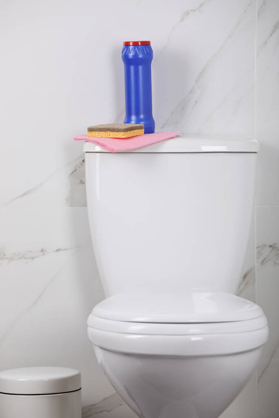 Bottle, sponge and cleaning rag on toilet bowl in bathroom - 写真・画像