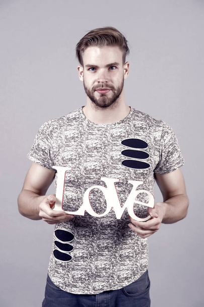 Man with serious face hold wooden love word, design. Valentines day concept. Love, romance, proposal. Valentine, valentines, holiday, celebration. Design, decor, craft. - Fotografie, Obrázek