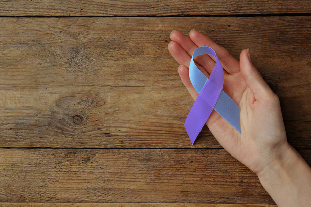 World Arthritis Day. Woman with blue and purple awareness ribbon on wooden background, top view. Space for text - Valokuva, kuva